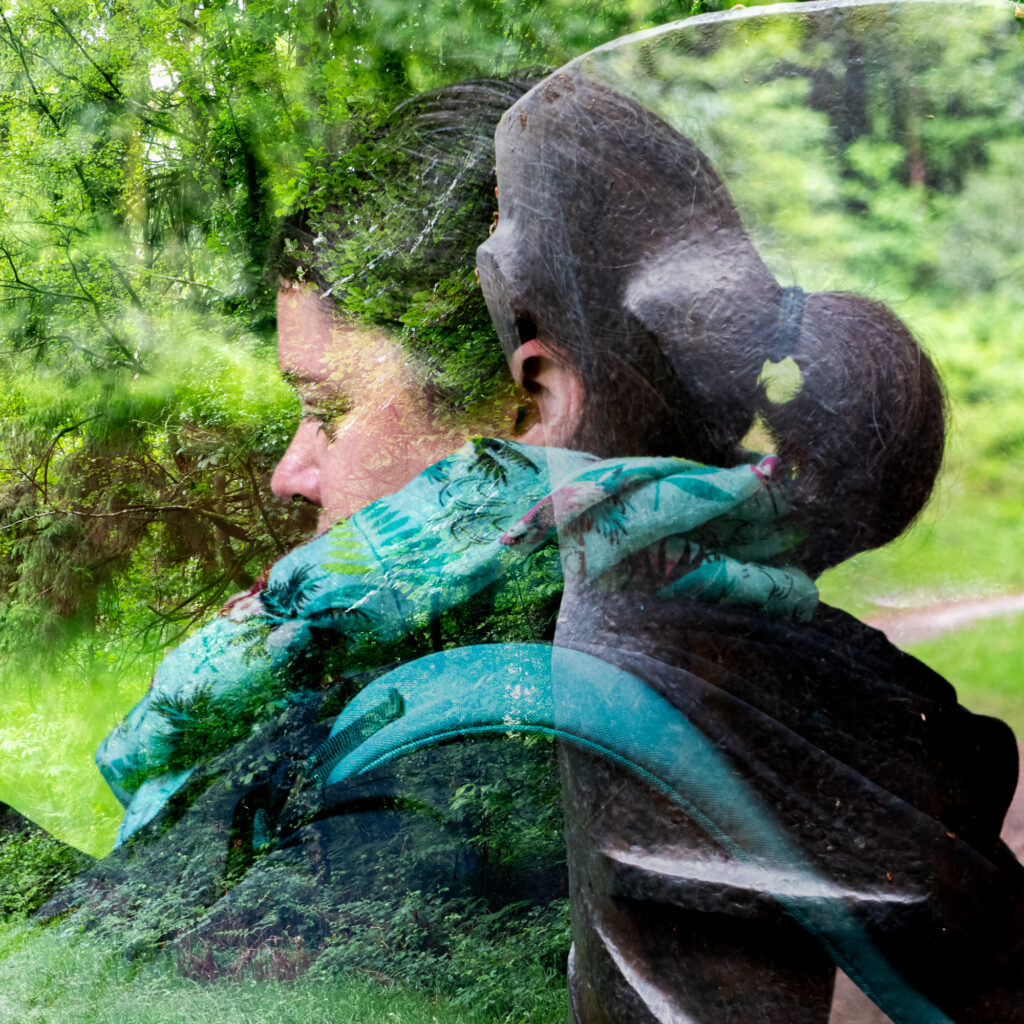 Une image en double exposition représentant une femme aux cheveux attachés en queue de cheval, vue de profil, sur laquelle se superpose une forêt d'un vert luxuriant, où son profil et son sac à dos se fondent avec les arbres et le feuillage.